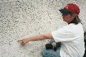 Jane Riedel at Law Enforcement Memorial pointing to P. O. Arthur Ohlsen's Name on Wall